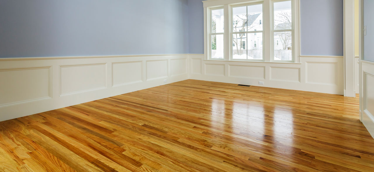 Hardwood floors in living room with a window and no furniture.