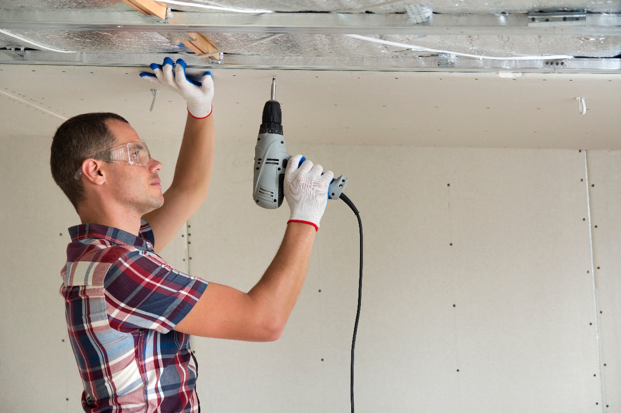 man fixing ceiling drywall