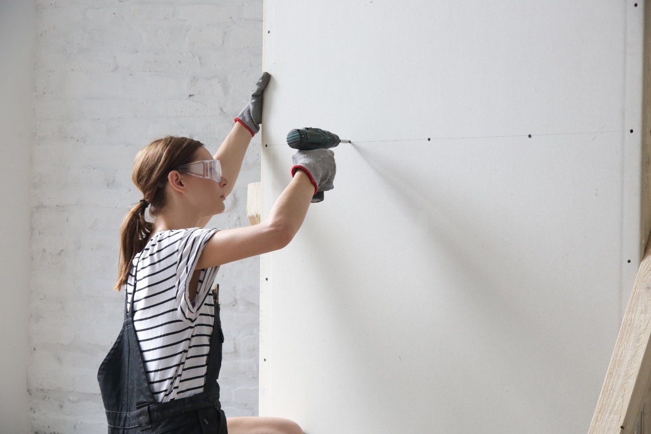 woman drilling screws into drywall 
