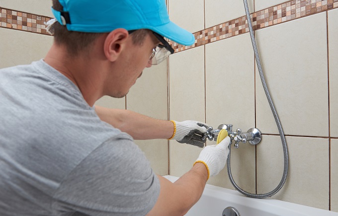 Cleaning bath service. Man in protective glasses polishing faucet
