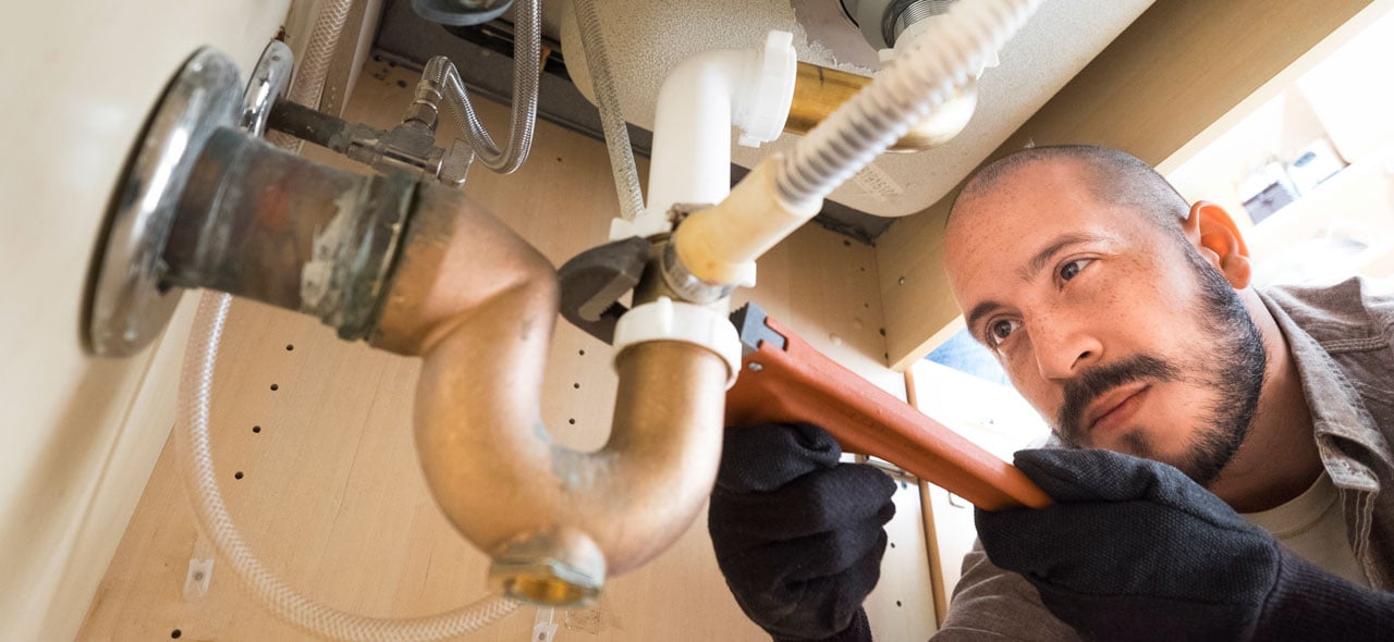 Plumber working under sink