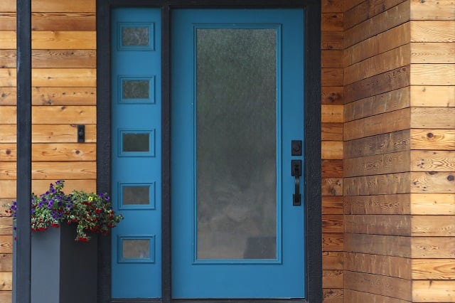 modern front door painted blue with matching transom window and wood siding