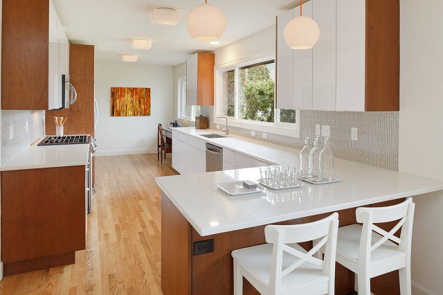 Gorgeous, newly-remodeled kitchen with wood cabinets and floors and white countertop bar