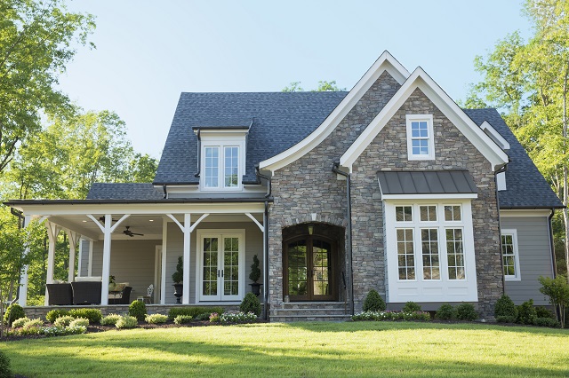 Front elevation of suburban, tudor-style home with partial stone veneer siding