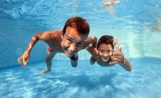 Underwater brothers portrait in swimming pool.