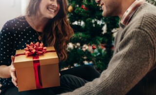 Young couple celebrating Christmas by exchanging gifts.