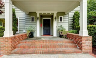 Painted black door in large entrance porch with columns and brick trim