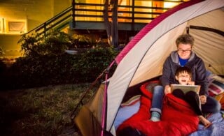 Mother and son using digital tablet in backyard tent