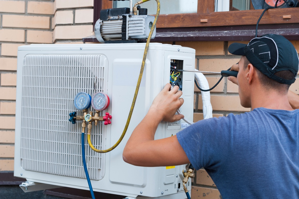 man installing ac unit outside home