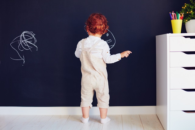 redhead boy drawing on the chalk wall at home