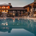beautiful large home with pool at dusk with lights on