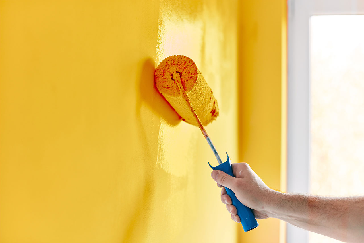 Hand painting yellow wall with a paint roller