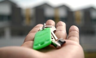 Hand holding keys in front of row of houses
