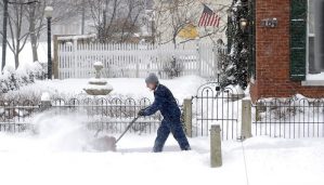 man uses a snow blower to remove snow from sidewalk