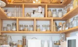 Woven baskets and food jars in pantry with built-in shelves