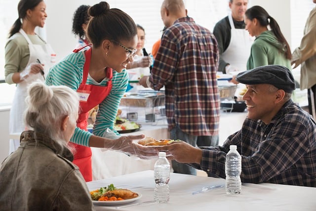 Volunteer helping the homeless by serving food at community kitchen