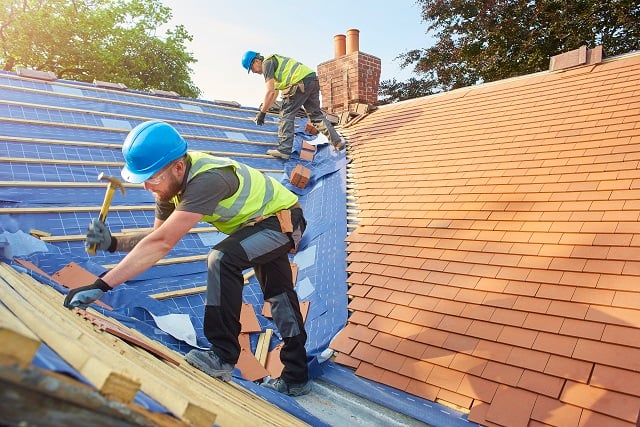 roofers nail down roof matting and tiles