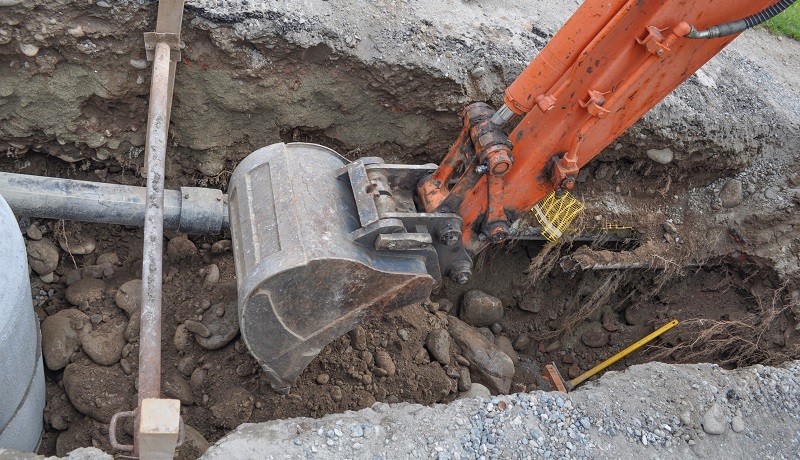 digger in a front yard for pipe laying