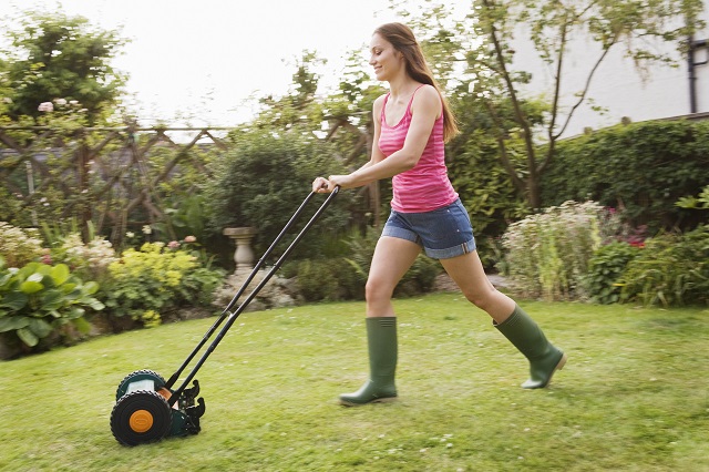 Woman mowing lawn with grass mower