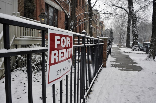 For rent sign on front fence of house in upscale urban neighborhood. The house is for rent during the depths of the winter season