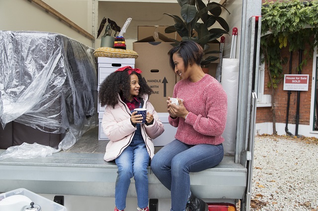 Mother and daughter drinking tea at back of moving van