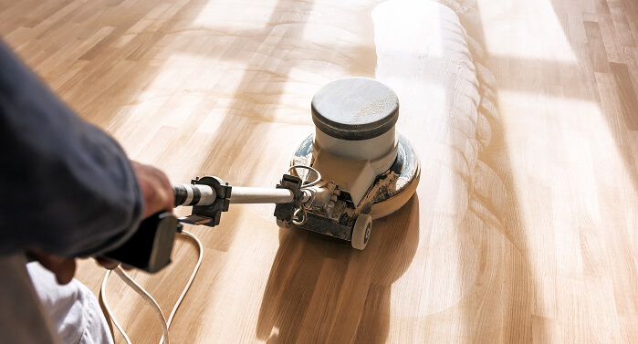 man buffer cleans laminate flooring
