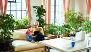 Grandfather and grandson on couch surrounded by live palms, ficus, and ferns.