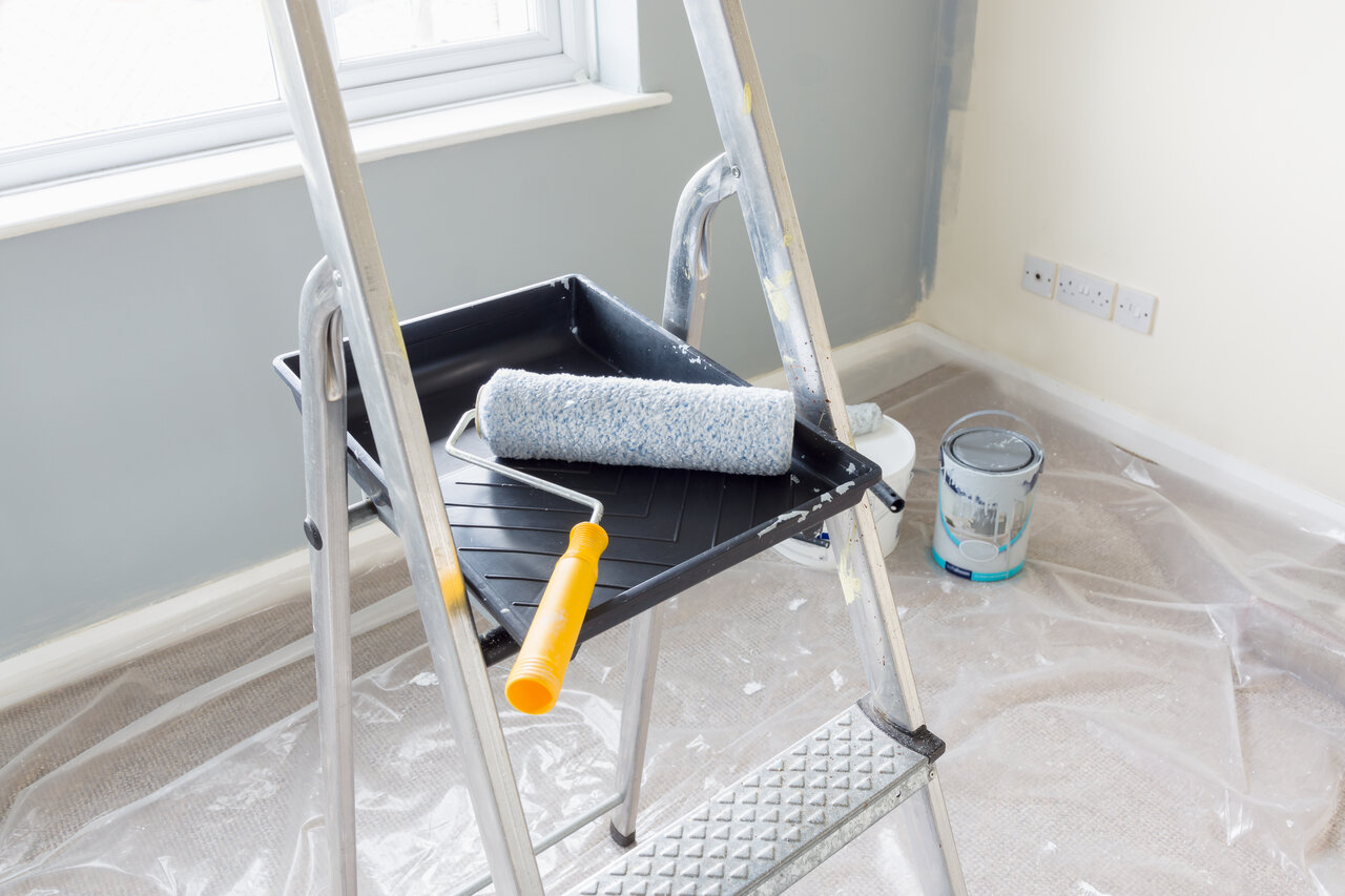 paint roller resting on tray on ladder