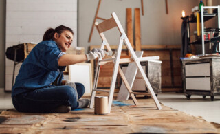 woman painting chair in garage