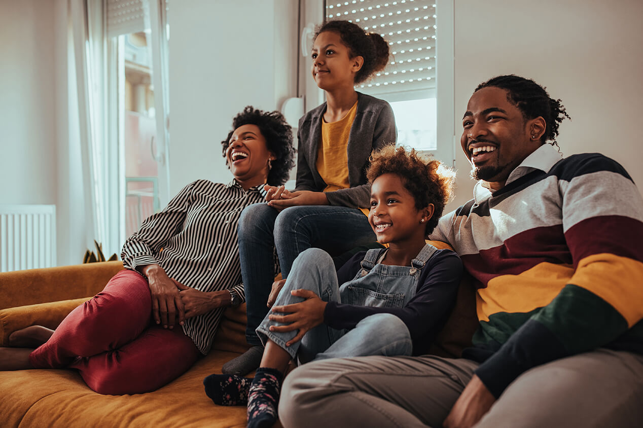 happy family watching movie on couch