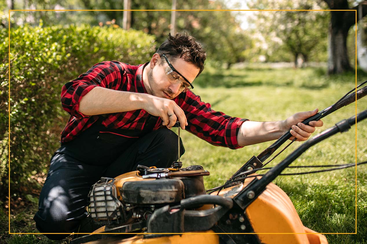 man with protective glasses on prepping a lawn mower