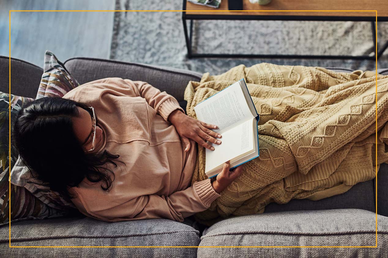 woman reading on couch with blanket 