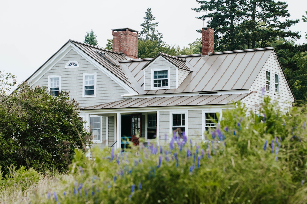 gray house with lush green garden in front under an overcast sky