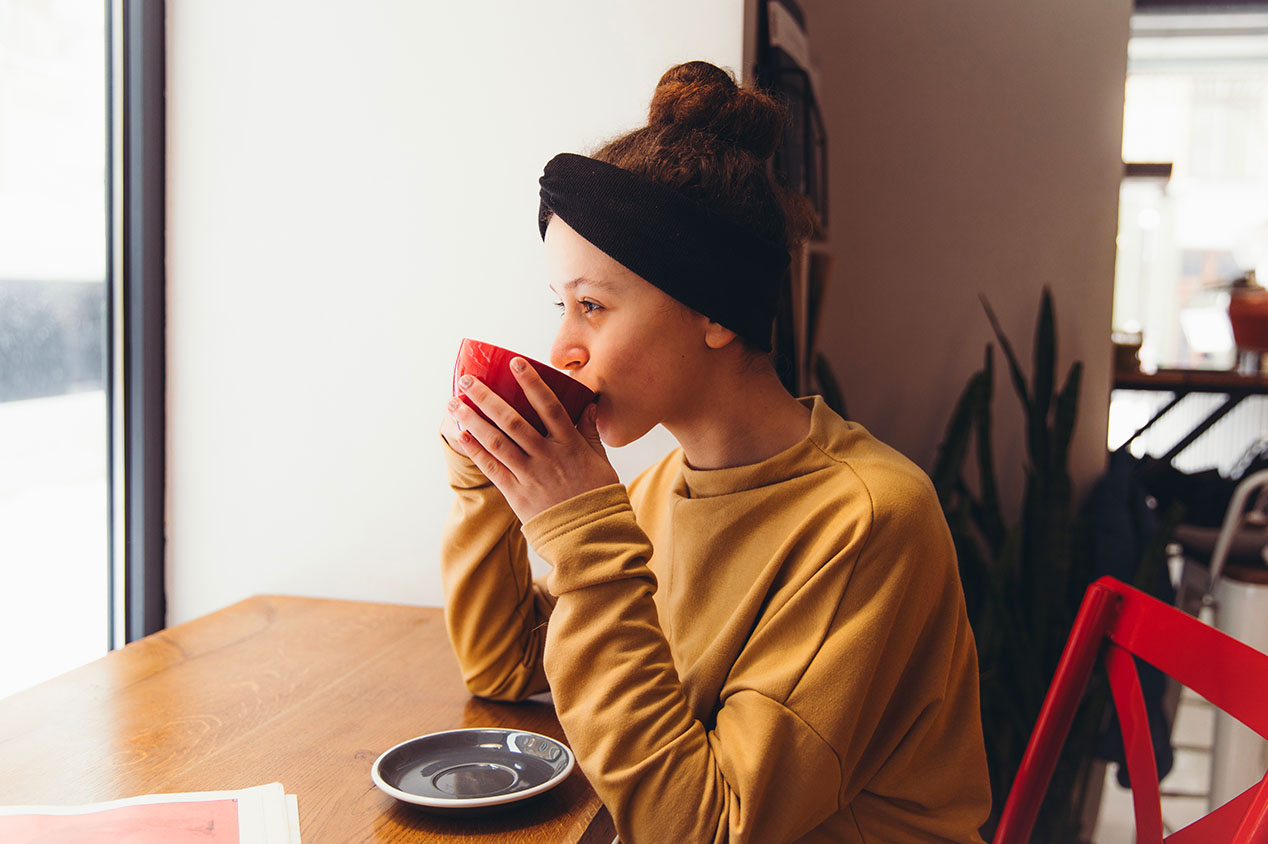 woman sipping coffee and looking out the window