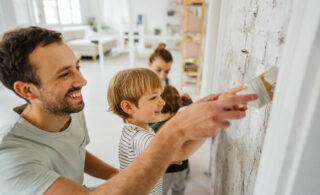father and son painting wall with mom