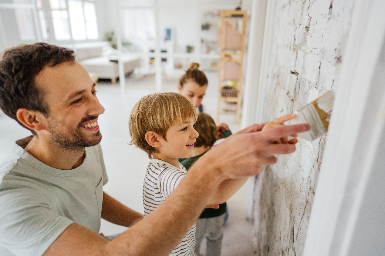 father and son painting wall with mom
