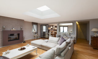 A living room with comfy sofa and a large skylight above it