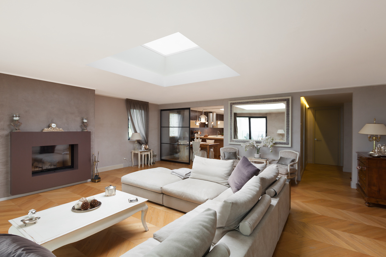 A living room with comfy sofa and a large skylight above it