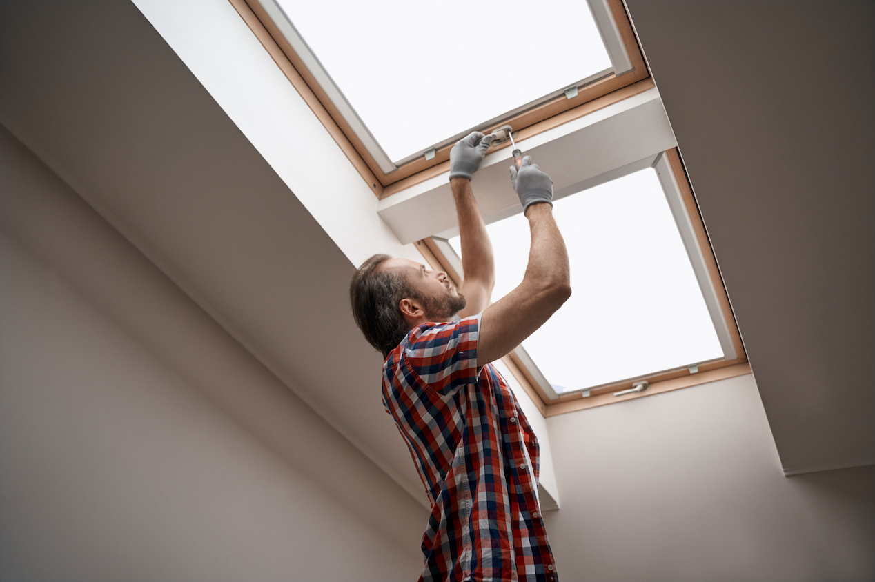 A man screwing a skylight window