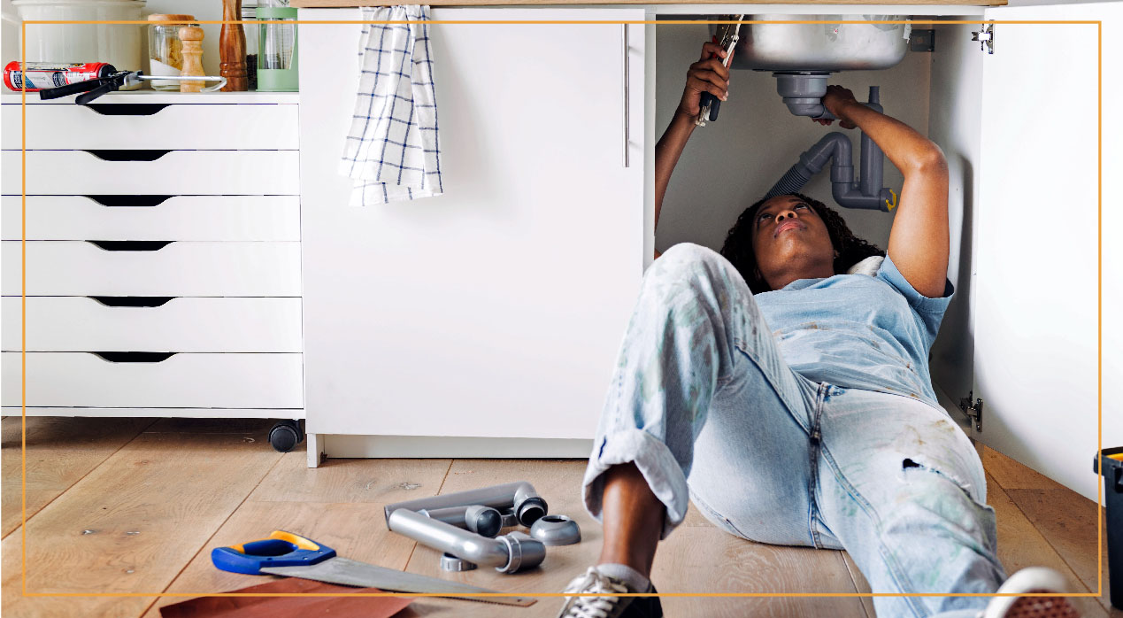 woman fixing plumbing under sink