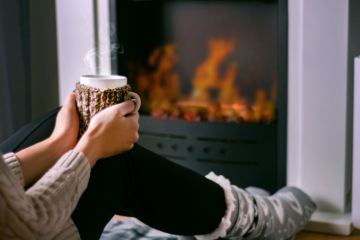 woman drinking tea near fireplace