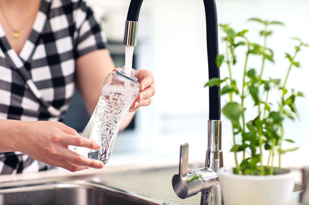 woman filling water bottle from tap